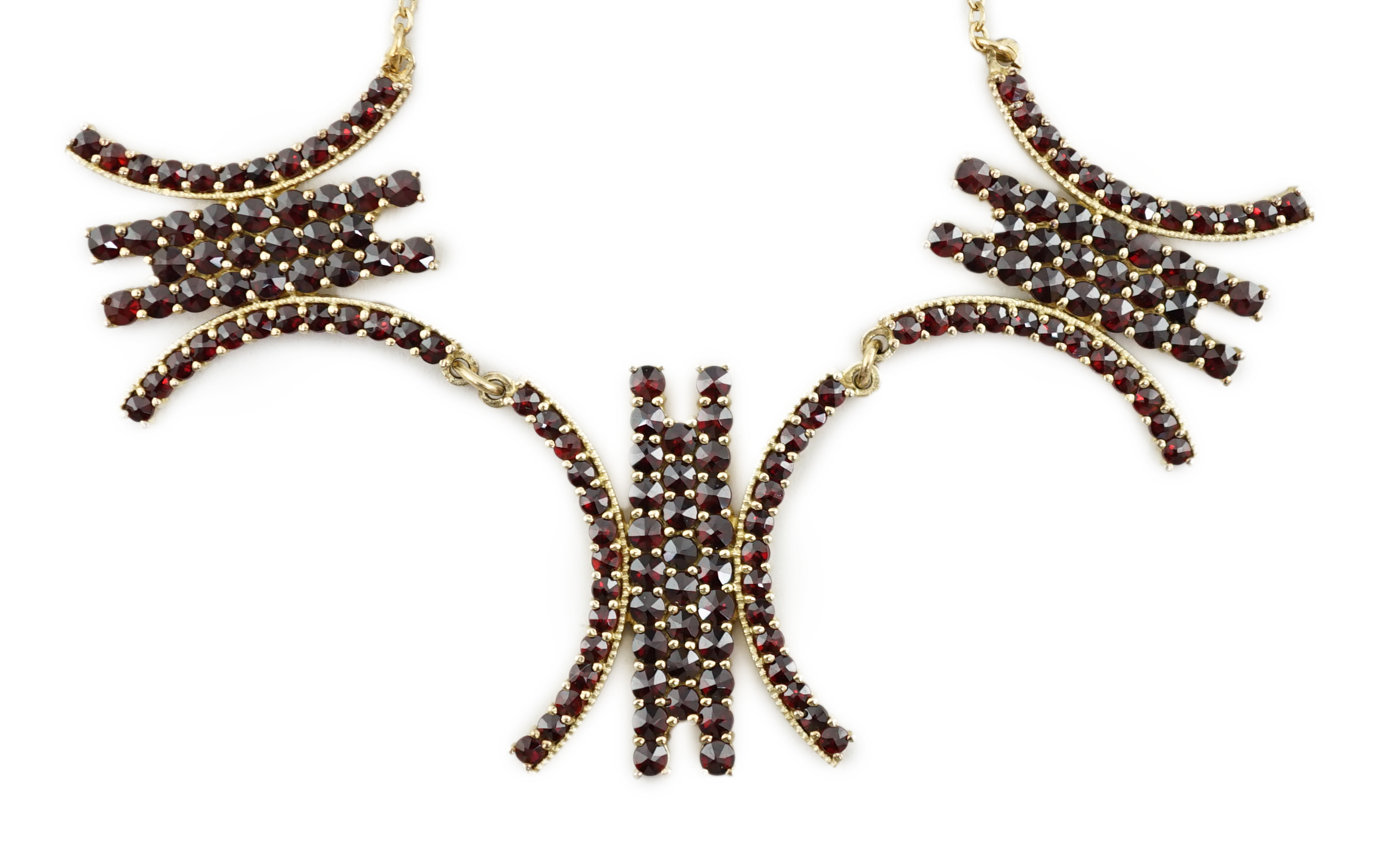 A yellow metal and garnet cluster set fringe necklace, with three stylised motifs, 45cm, gross weight 15.2 grams. Condition - fair to good